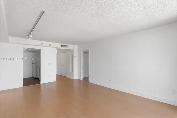 a view of a big room with wooden floor and windows