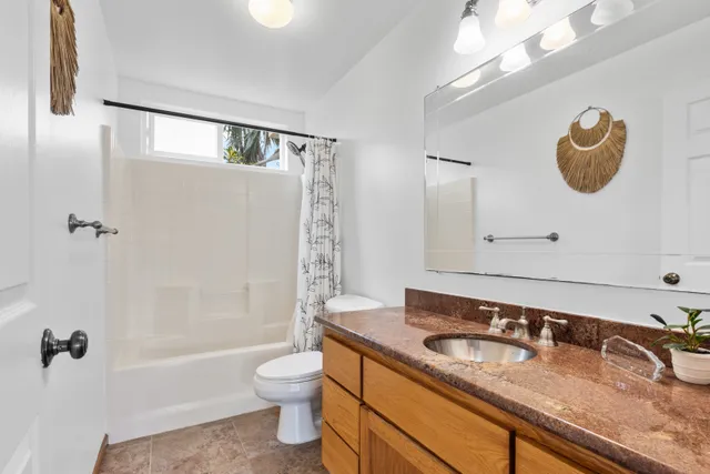 a bathroom with a granite countertop sink a toilet and shower