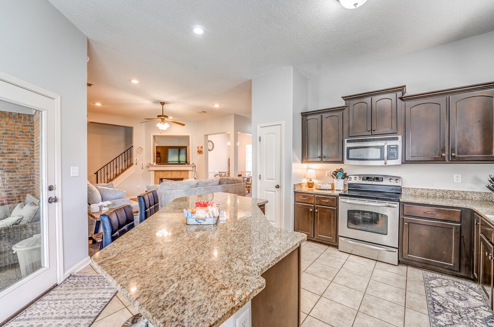 4671 Hampton Ridge Lane Bartlett, TN 38002 - Photo 20 of 40 Kitchen featuring an expansive island with a granite-style countertop, dark wood cabinetry, stainless steel appliances, and tiled flooring