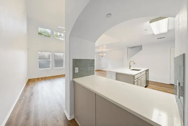a view of a kitchen with kitchen island a sink wooden floor and a large window