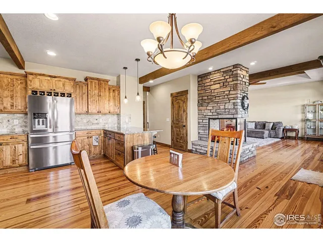 a dining room with stainless steel appliances kitchen island granite countertop a table chairs and a refrigerator