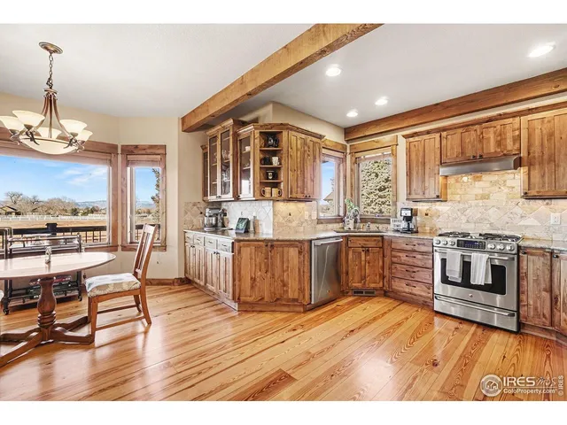 a kitchen with stainless steel appliances kitchen island granite countertop a stove top oven a sink a dining table and chairs with wooden floor