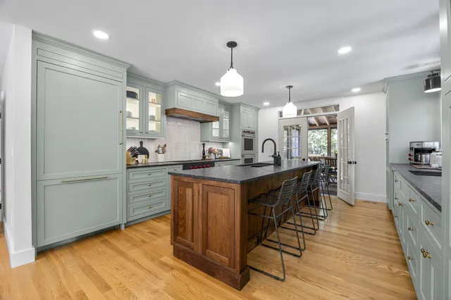 a kitchen with stainless steel appliances granite countertop a refrigerator a sink dishwasher a stove and white countertops with wooden floor