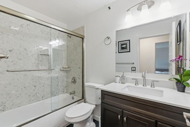 a bathroom with a granite countertop sink a toilet a mirror and shower