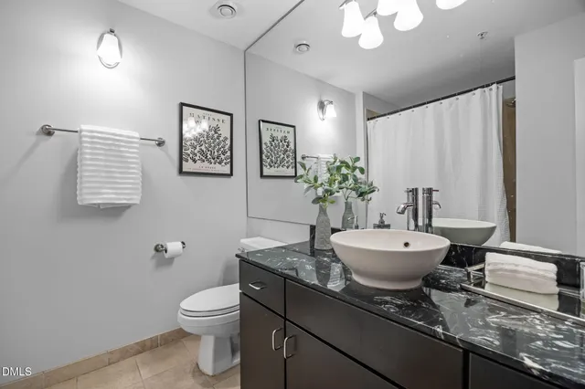 a bathroom with a granite countertop toilet sink and mirror