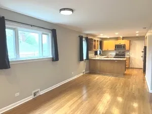 a view of a kitchen with kitchen island a sink wooden floor and a large window