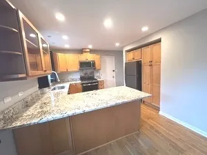 a kitchen with kitchen island granite countertop wooden cabinets a refrigerator and a sink