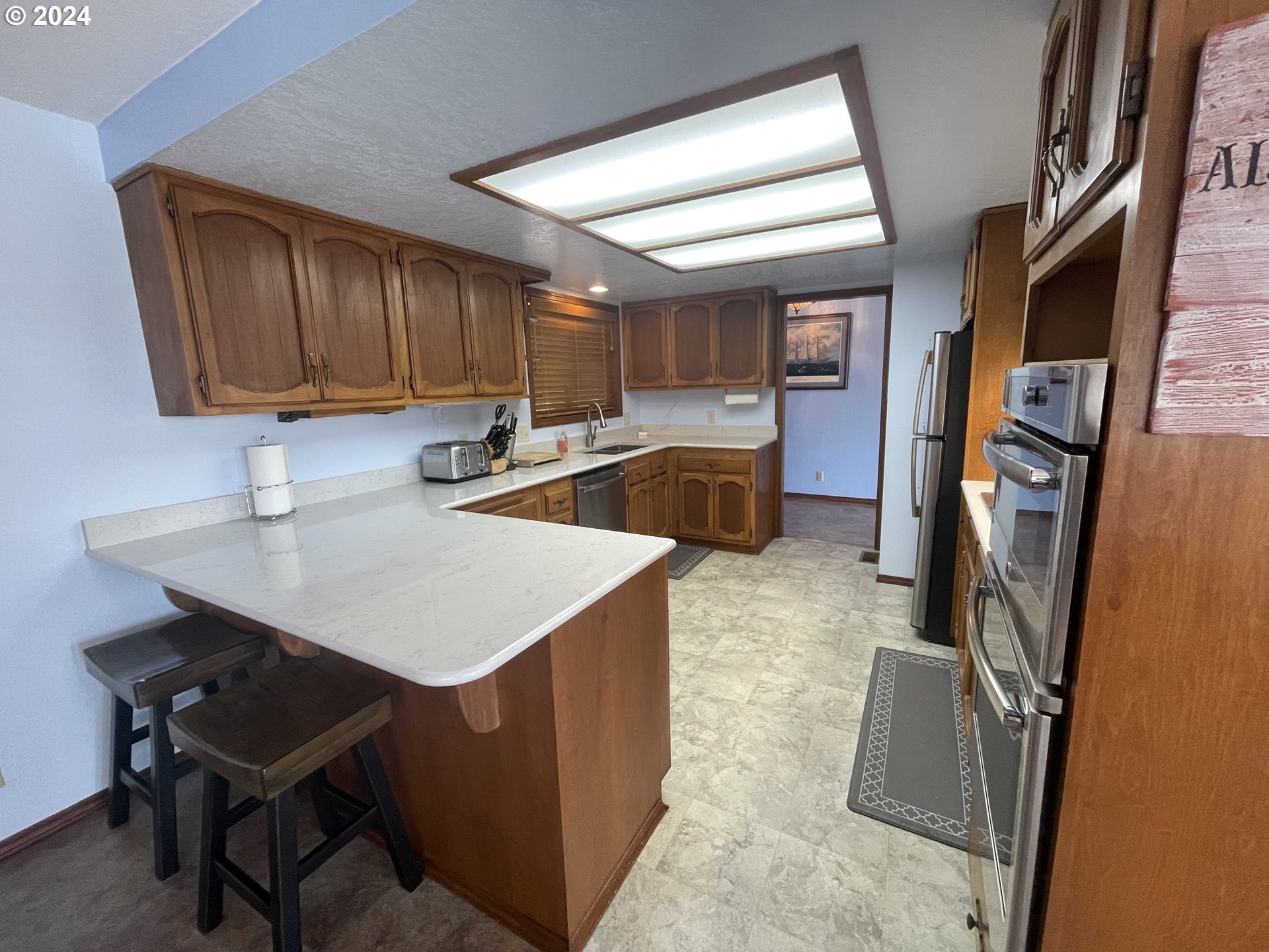 100 Rhododendron Drive Florence, OR 97439 - Photo 6 of 47 a kitchen that has a sink a microwave a refrigerator and chairs