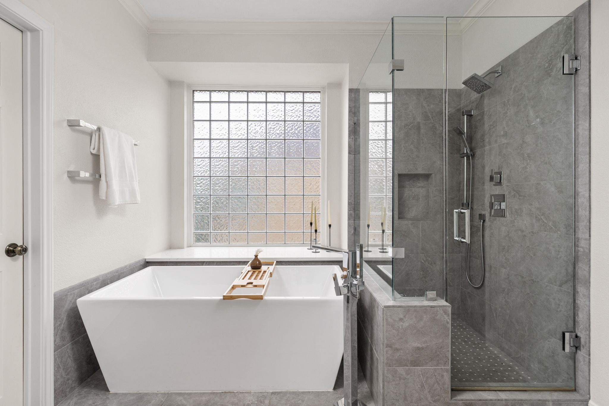 2807 Round Table Road Austin, TX 78746 - Photo 18 of 40 Freestanding soaking tub with a glass block window backdrop, complemented by a walk-in shower featuring a frameless glass enclosure, tiled walls, and multiple shower heads