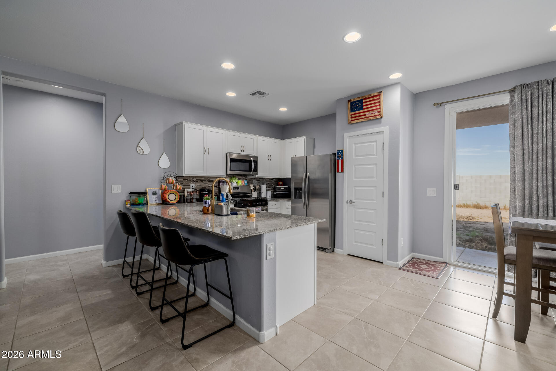 10918 West Atlantis Way Tolleson, AZ 85353 - Photo 7 of 20 a kitchen with stainless steel appliances kitchen island granite countertop a refrigerator and a sink