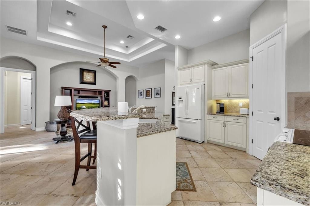 7793 Ashton Road Naples, FL 34113 - Photo 14 of 50 a kitchen with stainless steel appliances kitchen island granite countertop a refrigerator and microwave