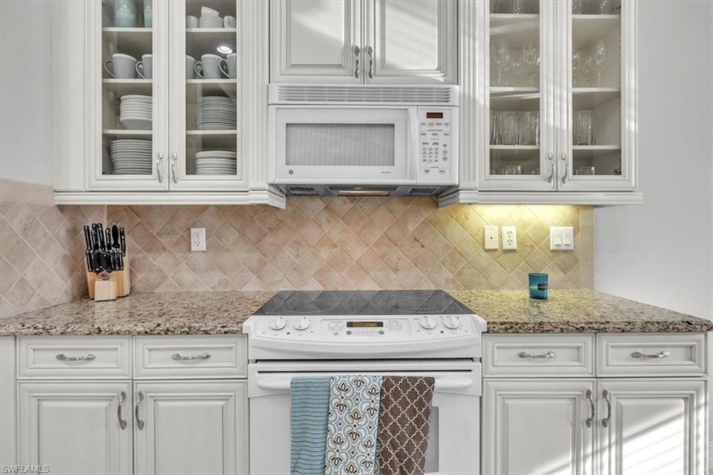 7793 Ashton Road Naples, FL 34113 - Photo 16 of 50 a kitchen with granite countertop white cabinets and a stove
