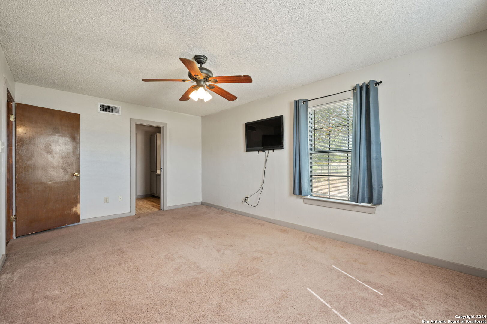 795 Highway 16 Jourdanton, TX 78026 - Photo 17 of 25 an empty room with windows and a chandelier fan