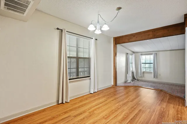 an empty room with chandelier fan and windows