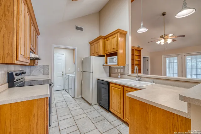 a kitchen with a sink a refrigerator and chandelier