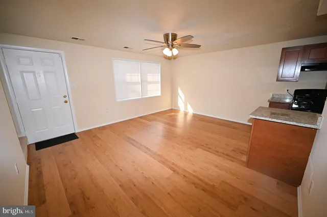 a view of an empty room with window and wooden floor