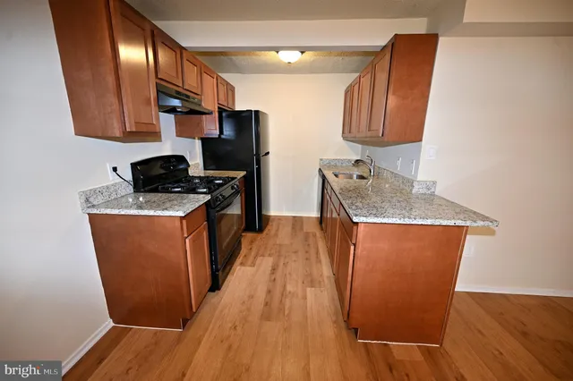 a kitchen with stainless steel appliances granite countertop a stove a sink a refrigerator and wooden floor