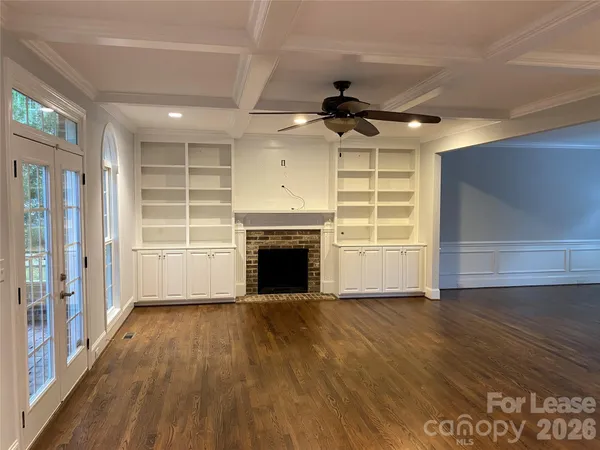 a view of an empty room with wooden floor fireplace and a window