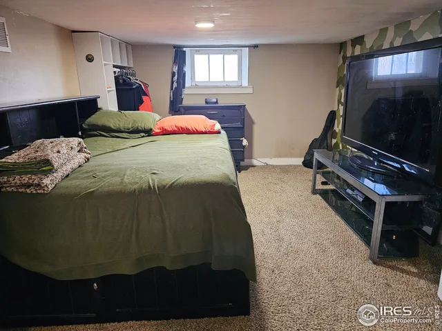 a bedroom with a bed and a flat tv screen on dresser