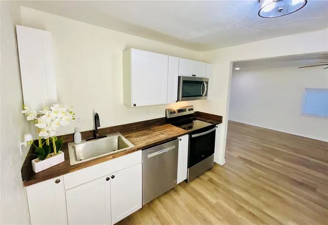 a kitchen with granite countertop a sink cabinets and stainless steel appliances