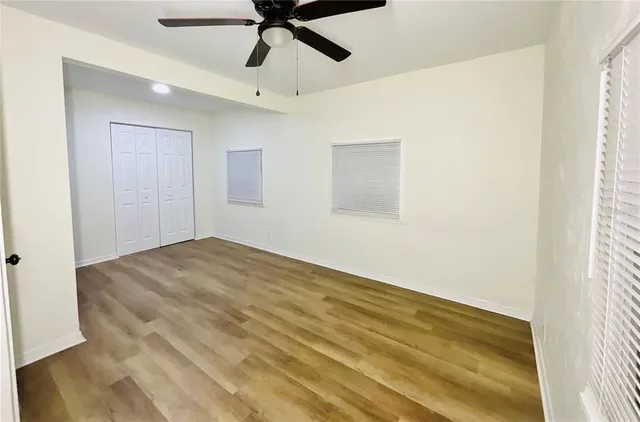 a view of empty room with wooden floor and fan