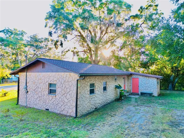 a view of a house with a yard and large tree