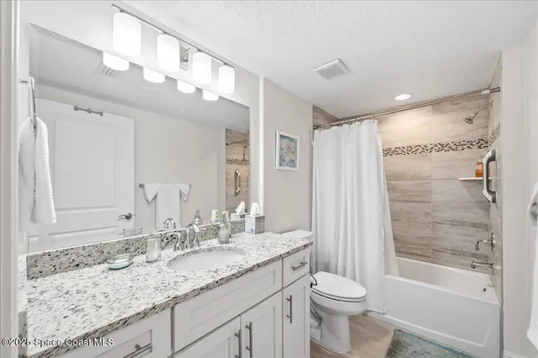 a bathroom with a granite countertop sink toilet and shower