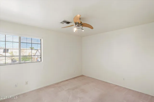 an empty room with windows and fan