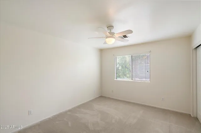 an empty room with a window and a ceiling fan