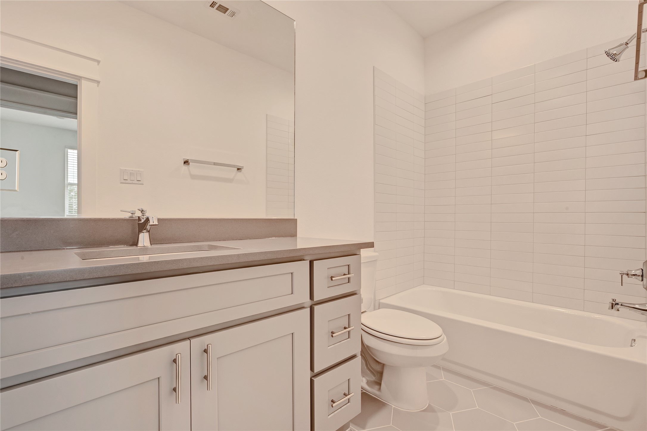 728 East 38th Street Houston, TX 77022 - Photo 13 of 18 Modern secondary bath featuring a sleek vanity with ample storage, large mirror, contemporary fixtures, and a tub/shower combo with tile surround for a clean, inviting feel.