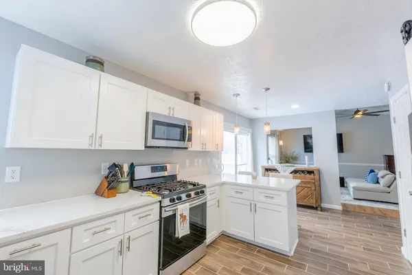a kitchen with stainless steel appliances granite countertop a sink dishwasher stove and white cabinets with wooden floor