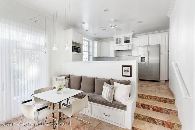 a living room with stainless steel appliances furniture a rug and a kitchen view