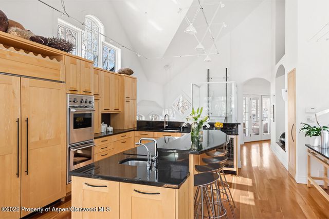 a kitchen with stainless steel appliances kitchen island granite countertop a table chairs and a refrigerator