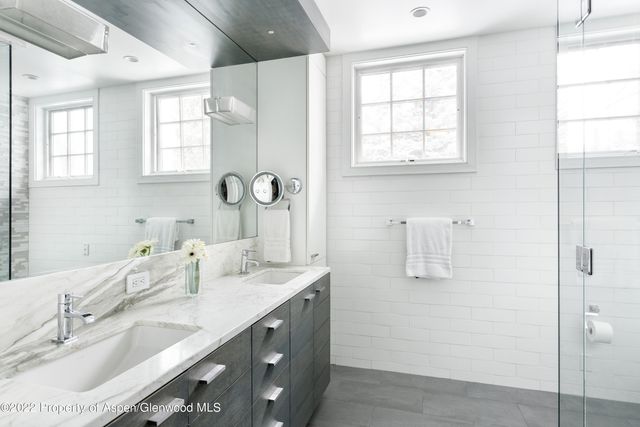 a bathroom with a granite countertop sink a mirror and a shower