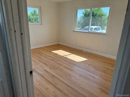 a view of empty room with window and wooden floor