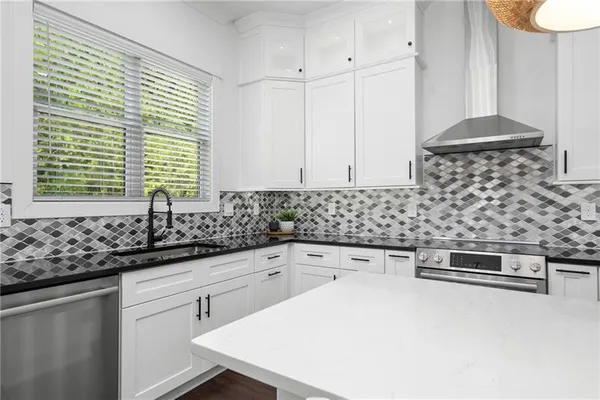 a kitchen with stainless steel appliances granite countertop a stove a sink a refrigerator and white cabinets with wooden floor