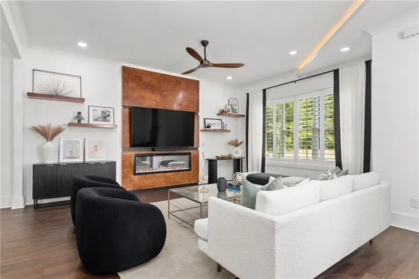 a living room with furniture a ceiling fan and a flat screen tv