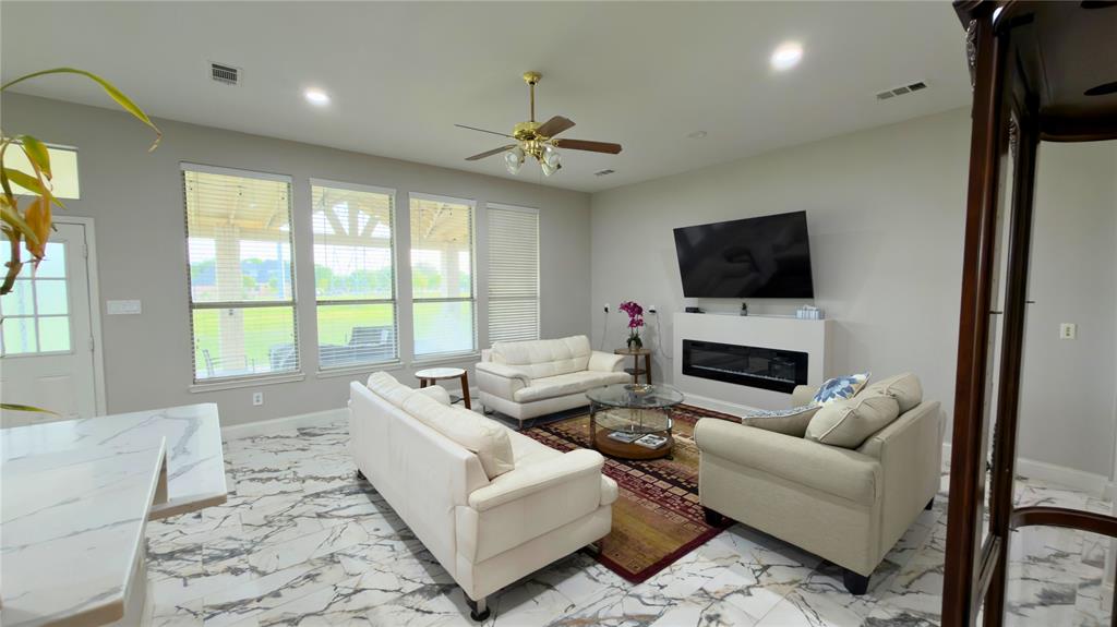 4303 Willow Ridge Drive Parker, TX 75002 - Photo 6 of 20 Living area with a glass covered fireplace, ceiling fan, recessed lighting, and light marble tile finish floors
