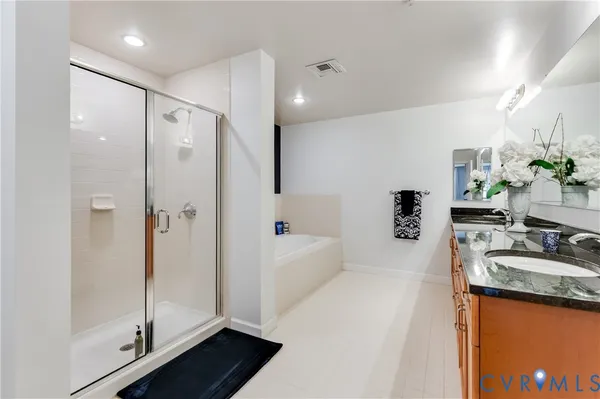 a bathroom with a granite countertop sink a mirror a bathtub and shower