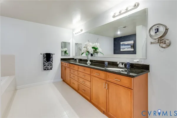 a spacious bathroom with stainless steel appliances granite countertop a sink and a bathtub