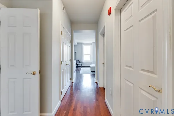 a view of a hallway with wooden floor and a bathroom