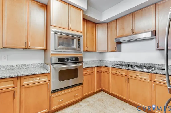 a kitchen with granite countertop cabinets stainless steel appliances and a counter space