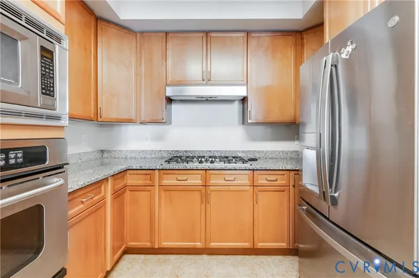 a kitchen with stainless steel appliances granite countertop a refrigerator and a stove