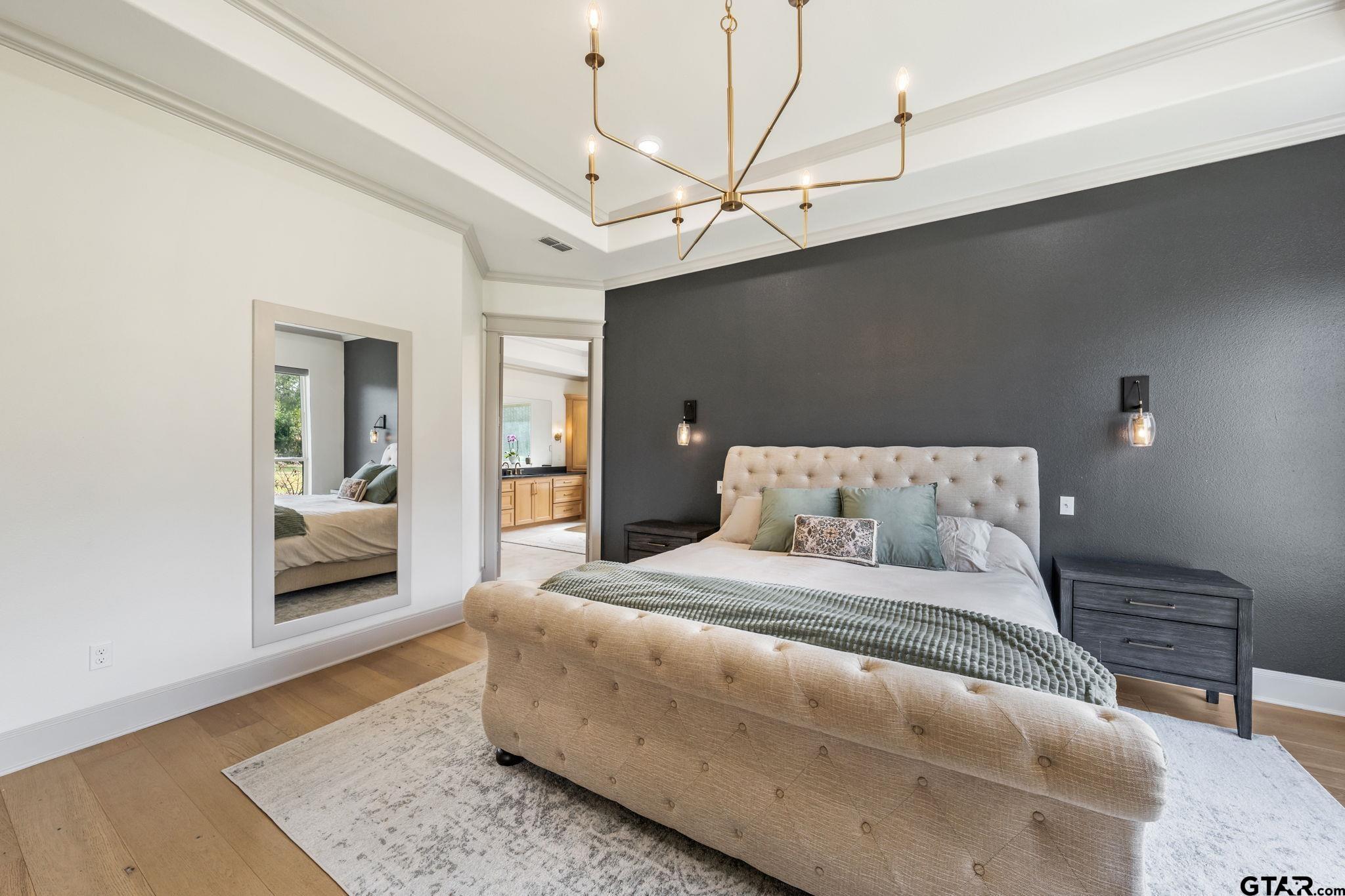 15601 Stampede Run Tyler, TX 75703 - Photo 21 of 48 a bedroom with a large bed and a chandelier