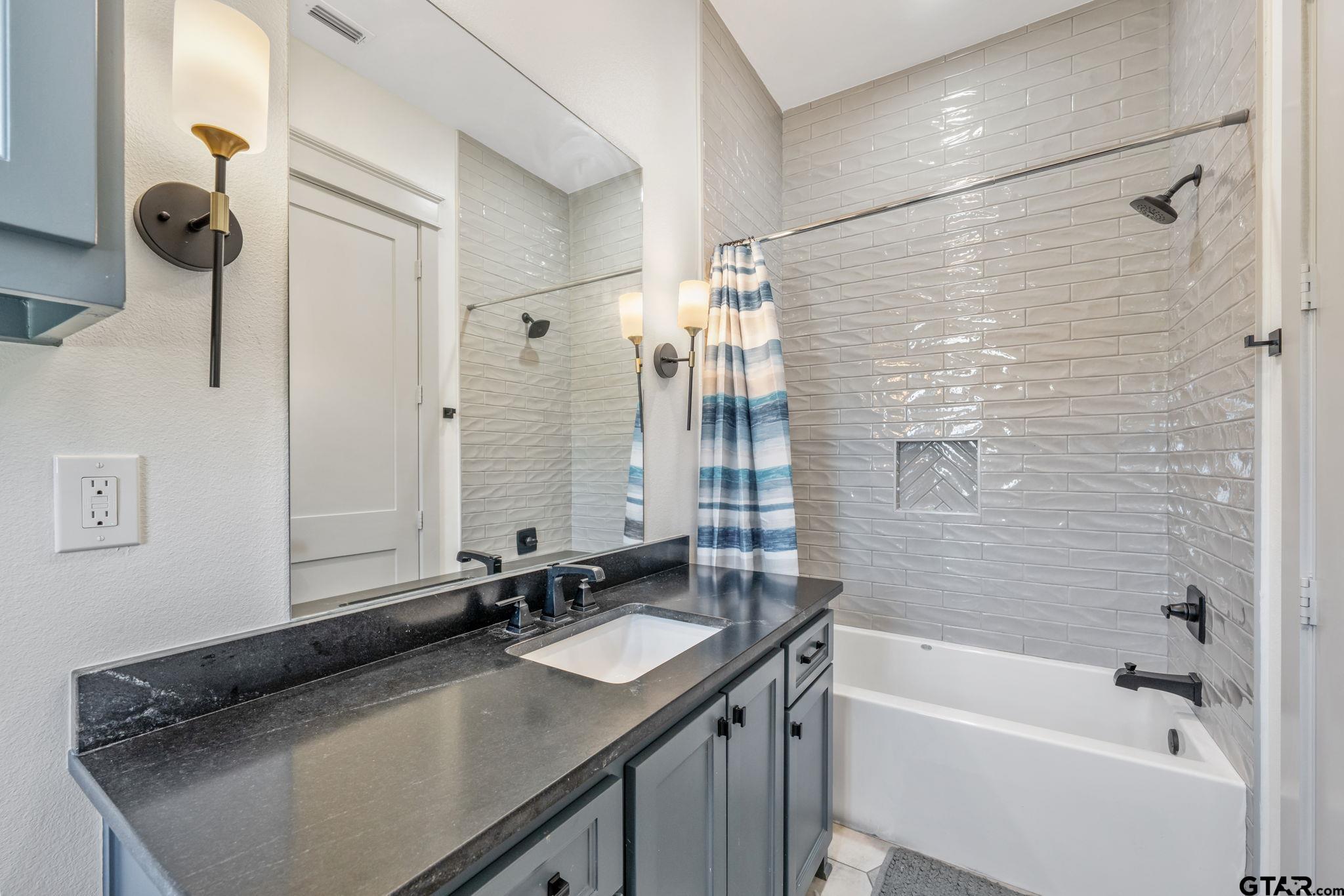15601 Stampede Run Tyler, TX 75703 - Photo 35 of 48 a bathroom with a granite countertop sink a mirror a bathtub and shower