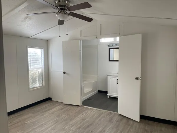 an empty room with wooden floor a ceiling fan and windows