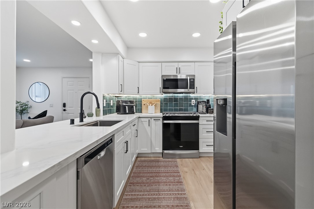 7950 West Flamingo Road, Unit 1180 Las Vegas, NV 89147 - Photo 12 of 26 Culinary aspirations come alive in this meticulously appointed kitchen, showcasing sleek cabinetry and a vibrant tile backsplash.