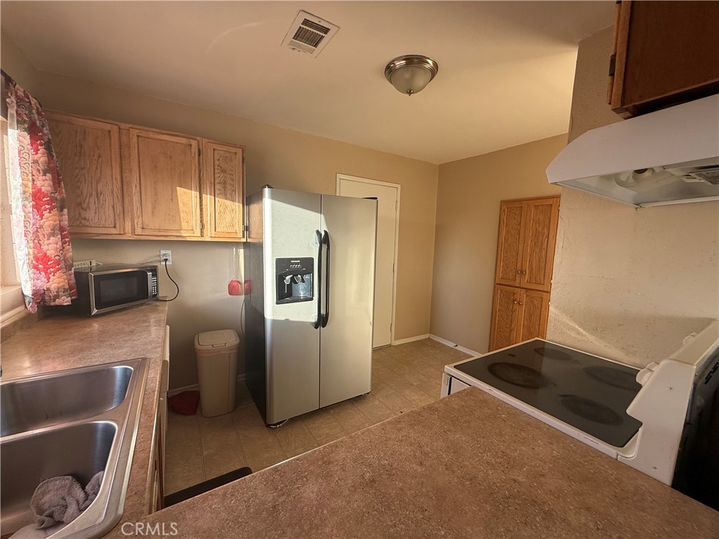 243 Balboa Avenue Mojave, CA 93501 - Photo 49 of 75 a kitchen with stainless steel appliances granite countertop a refrigerator and a stove top oven