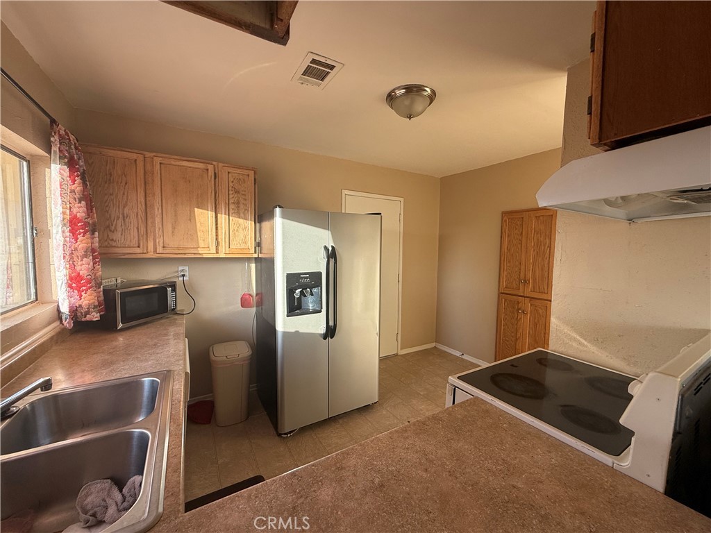 243 Balboa Avenue Mojave, CA 93501 - Photo 50 of 75 a kitchen with stainless steel appliances granite countertop a sink and a refrigerator