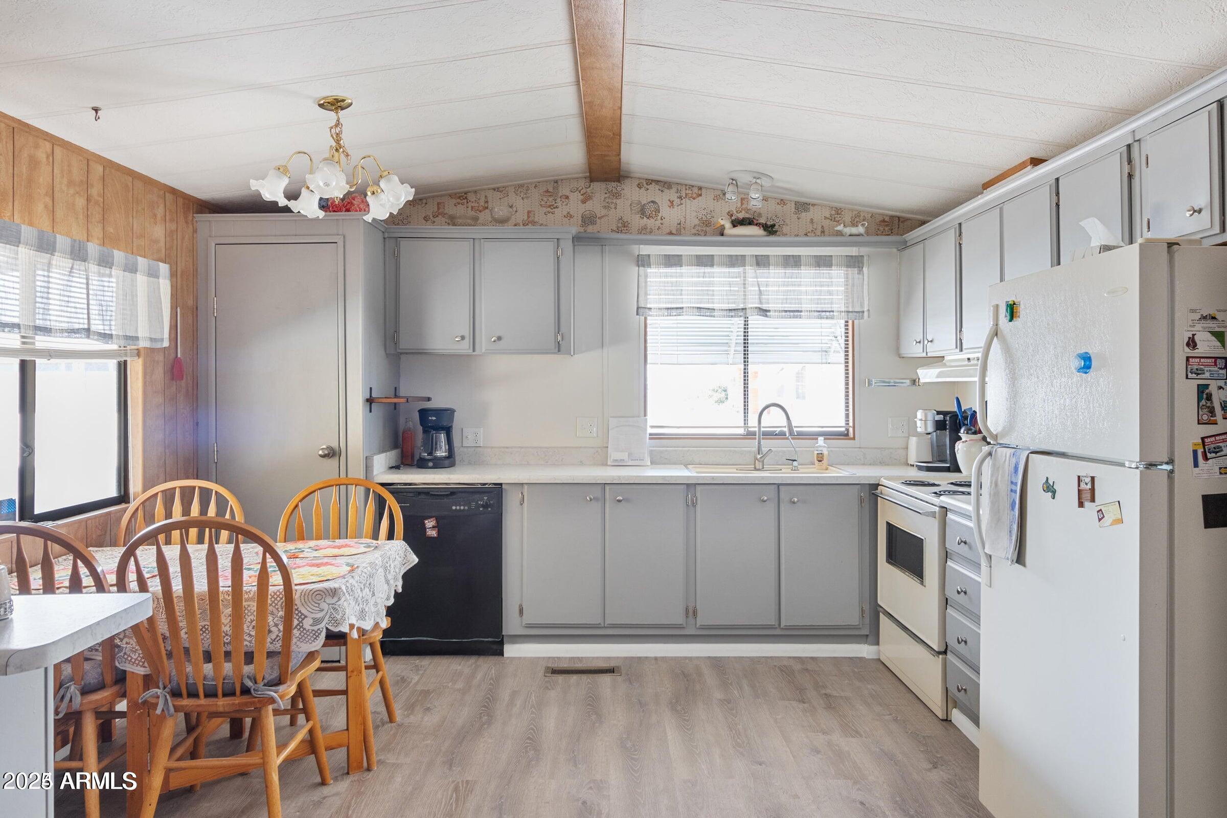 3330 East Main Street, Unit 9 Mesa, AZ 85213 - Photo 7 of 21 a kitchen with a refrigerator a sink dishwasher a stove and a dining table with wooden floor